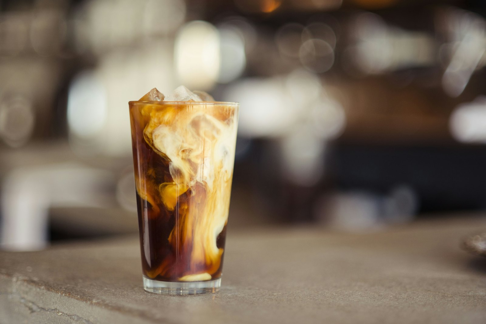 Iced coffee with cream swirling through it on the counter