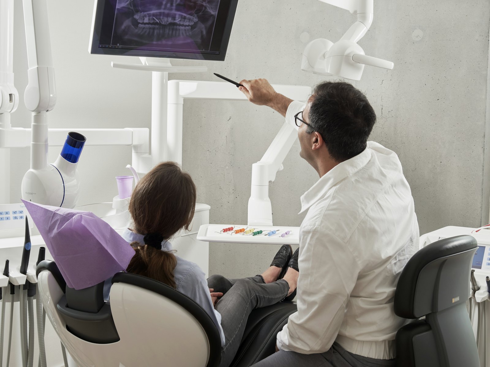 Dentist walking a patient through her digital X-ray on a chairside screen