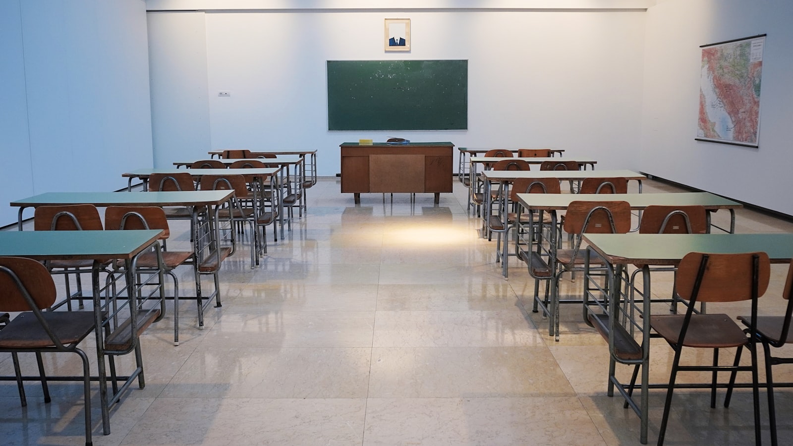 Bright, tidy classroom with rows of desks facing a green chalkboard