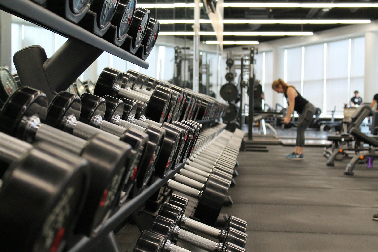 Rows of dumbbells on racks across a modern gym floor