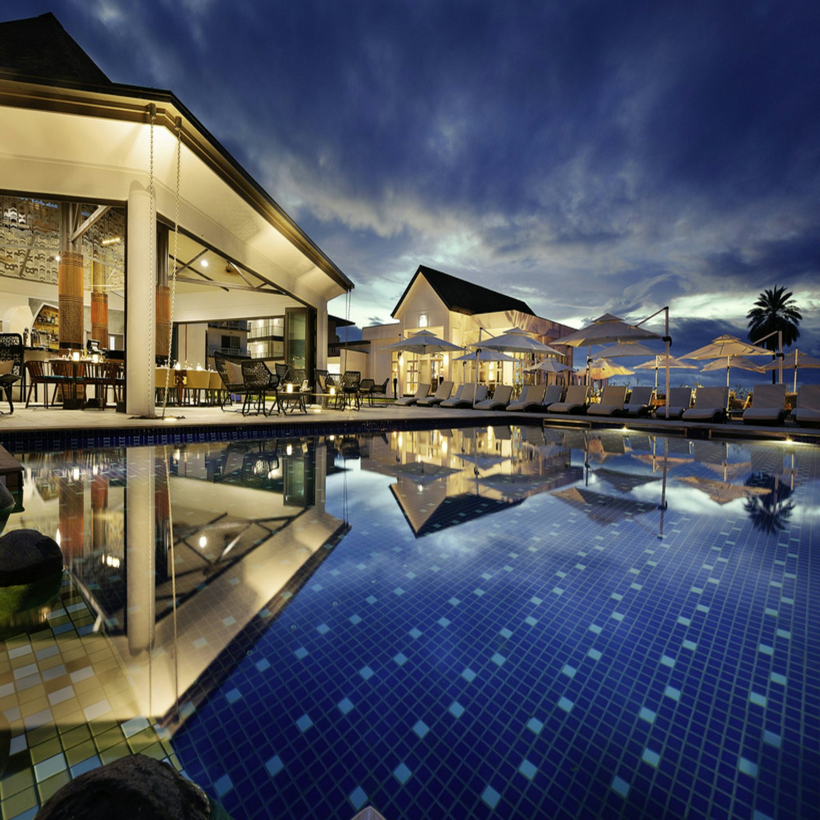 The Verandah's poolside pavilion glowing at dusk with candlelit tables