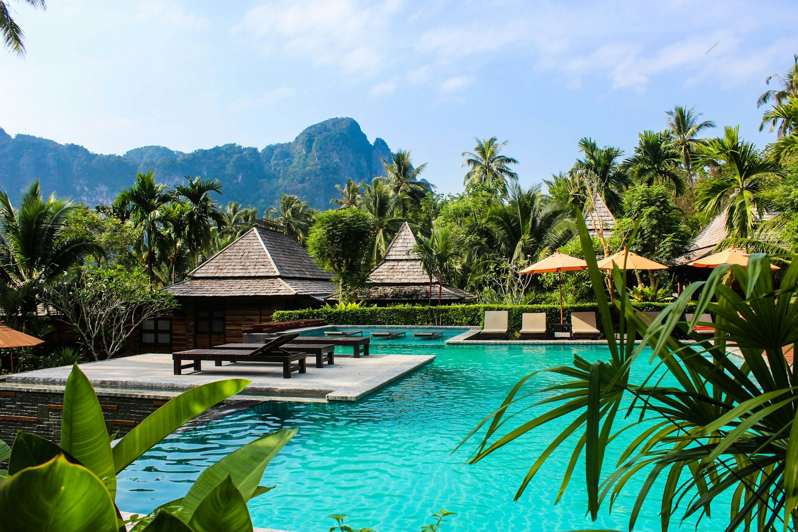 Turquoise garden pool framed by palms with limestone hills beyond