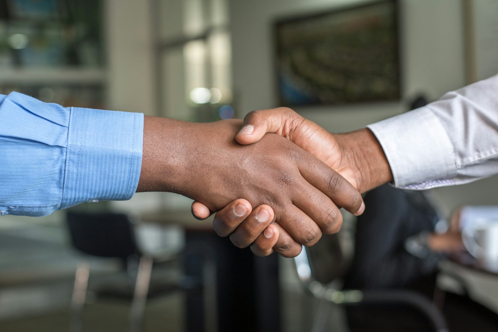 Two professionals shaking hands across a meeting room table