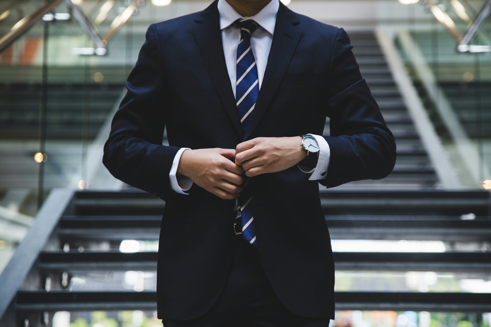 Partner in a tailored navy suit fastening his jacket