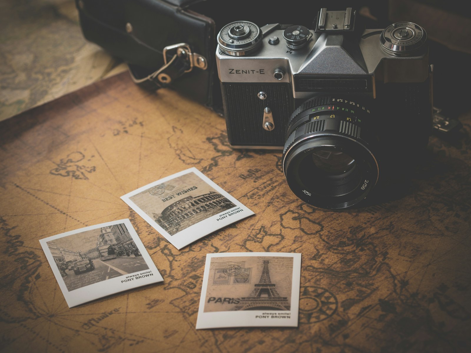 Vintage film camera and travel polaroids arranged on an antique world map