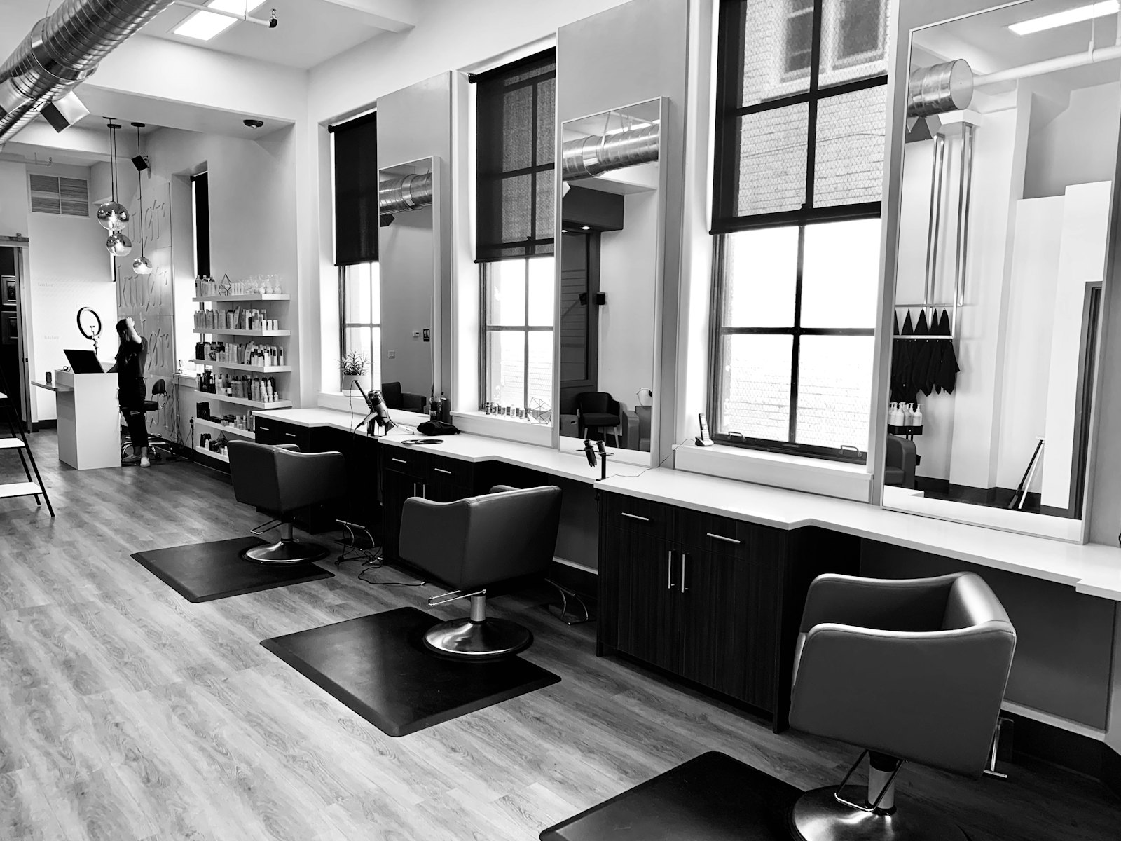 Sunlit row of styling stations with tall mirrors and leather chairs inside the studio