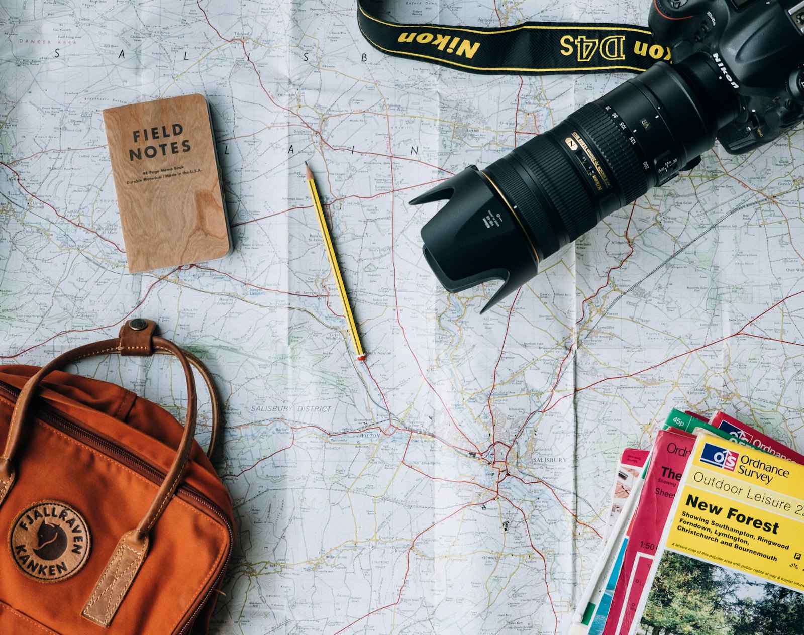 Trip planning flat lay with a paper map, camera, notebook and backpack