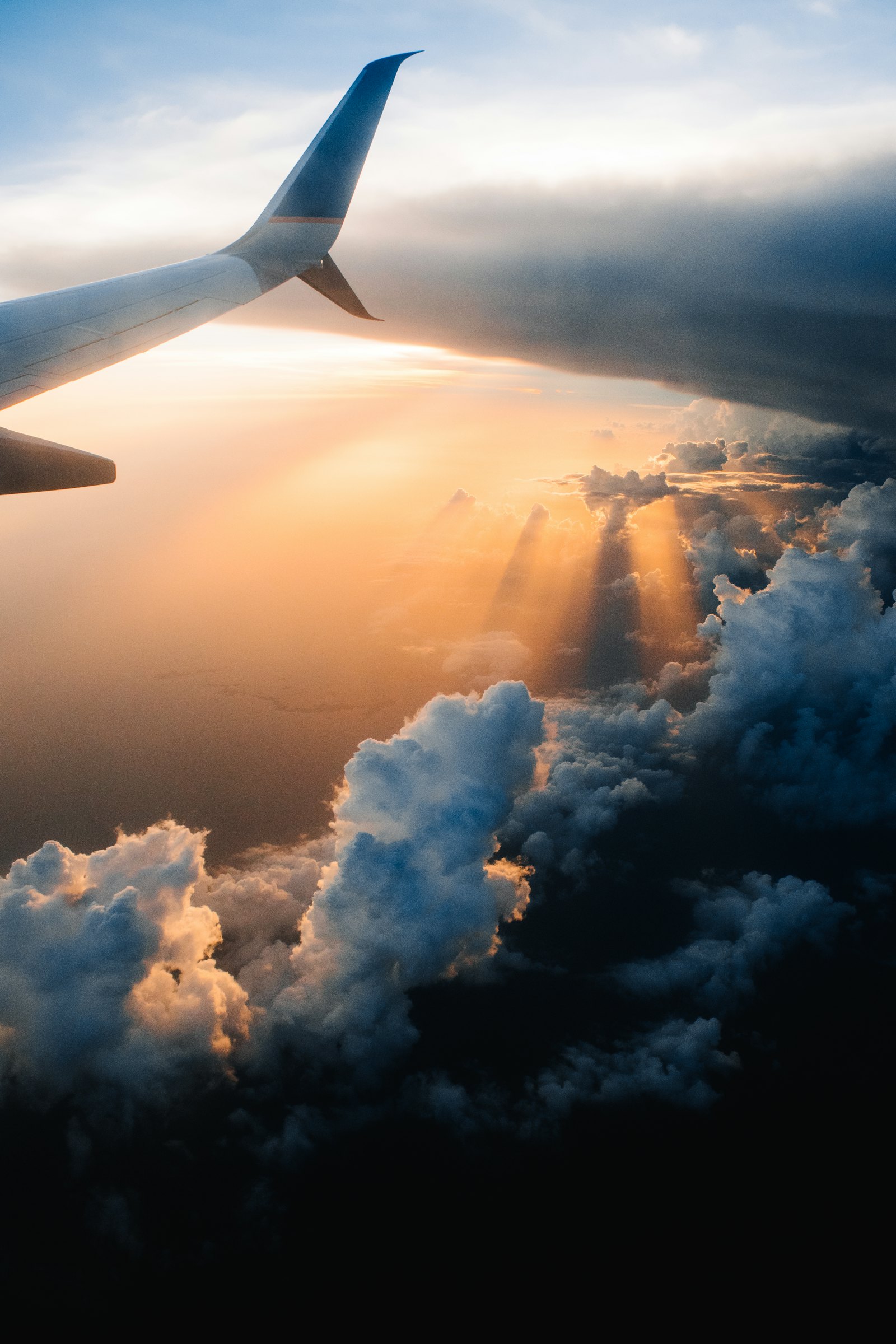 Airplane wing above golden sunset clouds seen from the window seat